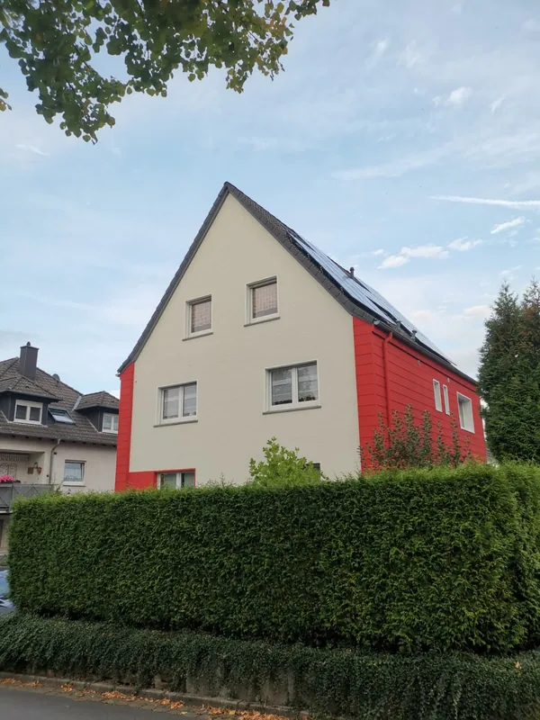 Rote und helle Fassade am gemeinsamen Standort von Makoa und Ohana hinter einer Hecke
