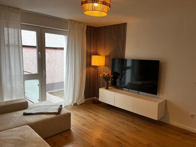 Wohnbereich am gemeinsamen Standort von Makoa und Ohana mit Sofa, Fernseher und Zugang nach draußen